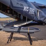 An Anduril Barracuda-500M stand-off cruise missile pictured beside a KC-390 Millennium tanker-transport aircraft at FIA 2026, where an MoU was signed on integrating a pallet-launched Barracuda-500M onto the Millennium. (Embraer)